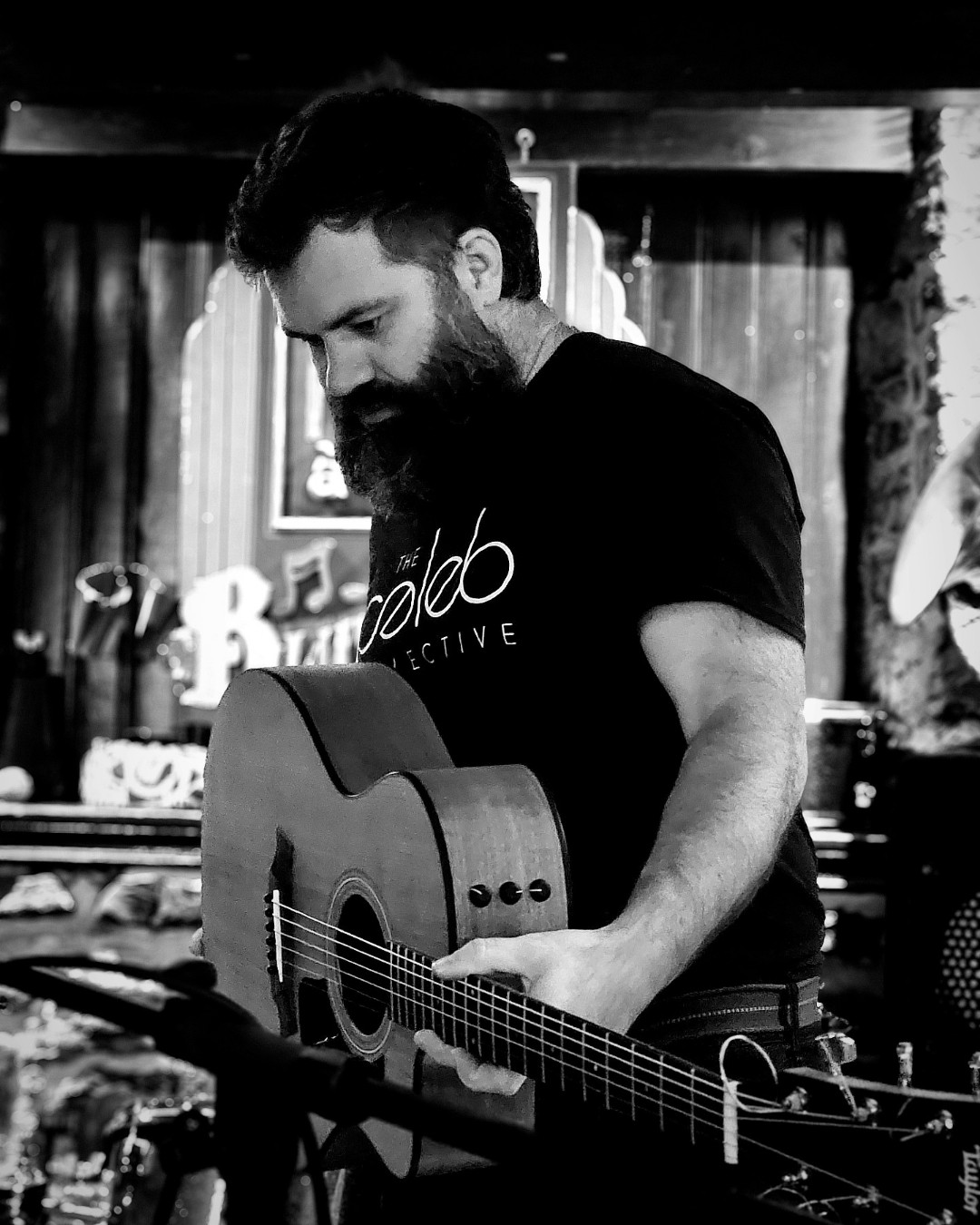 Caleb Taylor with his acoustic guitar in black and white